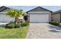 Inviting home features a lush, manicured lawn and a pristine two-car garage with paver driveway at 3764 Laughing Dove Ave, Sun City Center, FL 33573