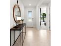 Inviting hallway with neutral tile flooring, console table, mirror and decorative lighting at 5703 Silverside Pine Ct, Lakewood Ranch, FL 34211