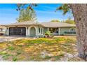 Inviting single-story home with a screened garage, lush front yard and charming arched entryway at 7660 Holiday Dr, Spring Hill, FL 34606