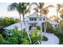 Beautiful two-story home with a circular driveway, lush landscaping, and a glimpse of the ocean at 770 N Manasota Key Rd, Englewood, FL 34223