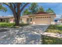 Beige one-story home with a well-maintained lawn, a two-car garage, and a clear blue sky at 11210 Wheeling Dr, Tampa, FL 33625