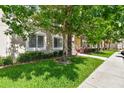 Exterior view of condo building with a tree, green lawn, and sidewalk at 1231 Godavari Way # 103, Wesley Chapel, FL 33543