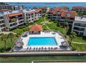 An aerial view of a community pool with lounge seating surrounded by lush tropical landscaping at 126 1St E St # 102, Tierra Verde, FL 33715