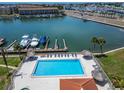 Aerial view of a community pool overlooking a marina, with a tiki umbrellas and lounge chairs at 126 1St E St # 102, Tierra Verde, FL 33715
