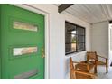 Close-up of front porch with a modern green door, wooden chairs, and large window at 5121 Flamingo N Dr, St Petersburg, FL 33714