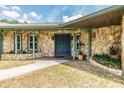 Inviting stone facade entryway with a blue front door and decorative landscaping accents at 6702 Towhe Dr, Seffner, FL 33584