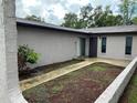 Exterior facade showcasing a front patio with mulch and small plants along the walls of the building with a door and sliding glass door at 1309 Malone Ave, Spring Hill, FL 34606