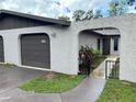 Gray home facade featuring an arched entryway leading to the front door with a storm door, gray walls, and manicured landscaping at 1309 Malone Ave, Spring Hill, FL 34606