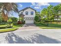 Beautiful two-story home with blue shutters, a two-car garage, and mature trees at 1341 Marinella Dr, Palm Harbor, FL 34683