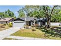 Charming single-story home featuring a gray exterior, well-manicured lawn, and mature shade trees at 14903 Winterwind Dr, Tampa, FL 33624