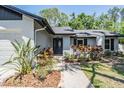 Inviting front entrance with decorative plants, a gray front door with oval window, and attractive landscaping at 14903 Winterwind Dr, Tampa, FL 33624