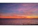 Scenic beach view with a pink and orange sunset and people walking along the shoreline at 15400 Gulf Blvd # 202, Madeira Beach, FL 33708