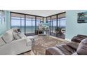 Bright living room with ocean views from floor to ceiling windows and a decorative palm rug at 15400 Gulf Blvd # 202, Madeira Beach, FL 33708