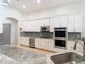 Open kitchen featuring white cabinets, stainless appliances, a wine cooler, and light-toned countertops at 15625 Hawks Crest Loop, Odessa, FL 33556