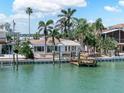 Waterfront property showcasing a cozy home with a boat dock surrounded by lush palm trees at 16353 Redington Dr, Redington Beach, FL 33708