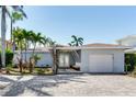 Charming single-story home with a two-car garage, lush landscaping, and a brick-paved driveway at 16353 Redington Dr, Redington Beach, FL 33708
