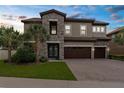 Elegant two-story home featuring stone accents, a three-car garage, a tile roof and a well manicured lawn at 21878 Amelia Rose Way, Land O Lakes, FL 34637