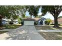 Image of a blue single Gathering home with a two-car garage and well-kept lawn, with shade from trees at 28818 Midnight Star Loop, Wesley Chapel, FL 33543
