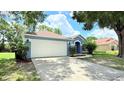 Charming single-story home with a blue exterior, mature landscaping, and an attached two-car garage at 28818 Midnight Star Loop, Wesley Chapel, FL 33543