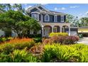 Charming two-story home with lush landscaping, colorful plantings and a welcoming front porch with columns at 3311 Home Ct, Tampa, FL 33611