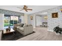 A bright living room boasts neutral tones, stylish wallpaper, wood floors and a ceiling fan at 3815 35Th S Way # 102, St Petersburg, FL 33711