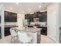 Modern kitchen boasts black cabinets, granite countertops, stainless steel appliances, and a center island at 4145 Shrewbury Pl, Land O Lakes, FL 34638