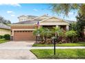 Charming home featuring a two-car garage, lush landscaping, a brick paved driveway, and a welcoming front porch at 5310 Sanderling Ridge Dr, Lithia, FL 33547