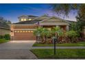 Charming home featuring a two-car garage, lush landscaping, a brick paved driveway, and a welcoming front porch at 5310 Sanderling Ridge Dr, Lithia, FL 33547