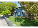 Beautiful exterior view of a blue two-story home, surrounded by lush greenery and a white picket fence at 701 14Th N St, St Petersburg, FL 33705