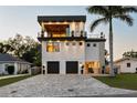 Modern three-story home featuring a private balcony, two-car garage, and a paver driveway at 706 S Davis Blvd, Tampa, FL 33606
