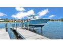 A boat is docked on a lift in the water with a small dock and blue skies at 729 Manns Harbor Drive, Apollo Beach, FL 33572