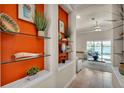 Bright hallway with an orange accent wall and glass shelving leading to a living room with water view at 729 Manns Harbor Drive, Apollo Beach, FL 33572