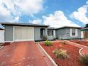 Single-story home with attached garage, a red driveway and decorative mulch landscaping at 8413 Moulton Dr, Port Richey, FL 34668