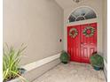 Inviting entryway features bright red double doors adorned with decorative wreaths and manicured shrubs at 1077 Captains Way, Tarpon Springs, FL 34689