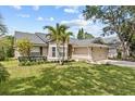 Attractive single Gathering home showcasing a well-kept lawn, mature trees, and a two-car garage at 1077 Captains Way, Tarpon Springs, FL 34689