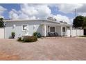 Charming single-story home with a large brick driveway, manicured landscaping, and quaint front porch seating at 2805 W Patterson St, Tampa, FL 33614