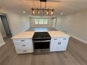 Open-concept kitchen featuring an island with a cooktop, a stylish lighting fixture, and plank flooring at 29813 69Th N St, Clearwater, FL 33761