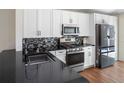 Bright kitchen featuring white cabinets, black countertops, stainless steel appliances, and a stylish backsplash at 302 Summer Sails Dr, Valrico, FL 33594