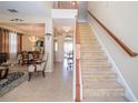 Inviting foyer featuring tile floors, staircase with wood banister and views of the living and dining areas at 30526 Annadale Dr, Wesley Chapel, FL 33545
