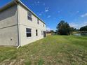 Back exterior showcasing a large grassy yard, lake view, and rear elevation of the two-story home at 3109 Chessington Dr, Land O Lakes, FL 34638