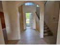 Foyer with tile flooring, staircase, and archway leading to the front door at 3109 Chessington Dr, Land O Lakes, FL 34638
