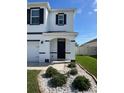 Front porch with dark door and minimal landscaping with grass and gravel beds at 32699 Dashel Palm Ln, Wesley Chapel, FL 33543