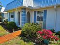 Charming single-story home with a blue metal roof, white exterior, and colorful flower beds at 4206 Tamargo Dr # 4206, New Port Richey, FL 34652