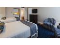 Bright bedroom featuring two beds, mini-kitchen and blue patterned accent chair at 5500 Gulf Blvd # 2249, St Pete Beach, FL 33706
