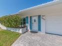 Close up of the home's entrance showcasing the door, blue shutters, and well-maintained landscaping at 9024 140Th Way, Seminole, FL 33776