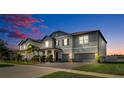 Dusk view of a beautiful two-story home with a well-manicured lawn and a brick driveway at 11720 Navajo Sandstone St, Riverview, FL 33579