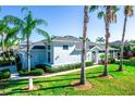 Light blue home with lush green lawn, tropical palm trees, and a screened-in lanai at 1257 Lyndhurst Greens Dr, Sun City Center, FL 33573