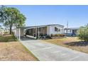 Single-story home featuring a covered parking area, screened-in porch, and neat landscaping at 37229 Cora Ave, Zephyrhills, FL 33542