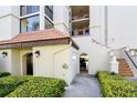 Condo exterior featuring tile roof, unit number, stairs to upper units, and mature landscaping at 7480 Bayshore Dr # 402, Treasure Island, FL 33706