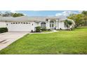 Beautiful single-story home featuring a lush green lawn and a charming front entrance with manicured landscaping at 8804 Poe Dr, Hudson, FL 34667